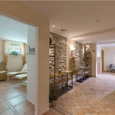 Ein helles, einladendes Eingangsbereich mit modernen Möbeln und dekorativen Elementen. Die Wände sind mit einem ansprechenden Steinmuster gestaltet.