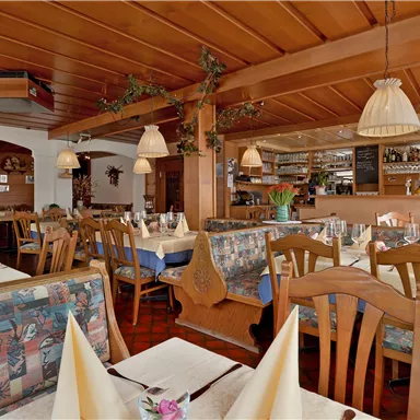 A cozy restaurant with wooden furniture and a warm ambiance. The tables are elegantly set and create an inviting atmosphere.