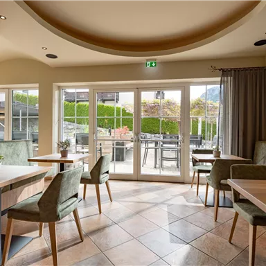 An inviting restaurant with large windows and modern furniture. The space is bright and friendly, ideal for social gatherings.