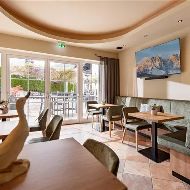 A cozy café with modern tables and chairs. Large windows provide a view of the outdoor area.