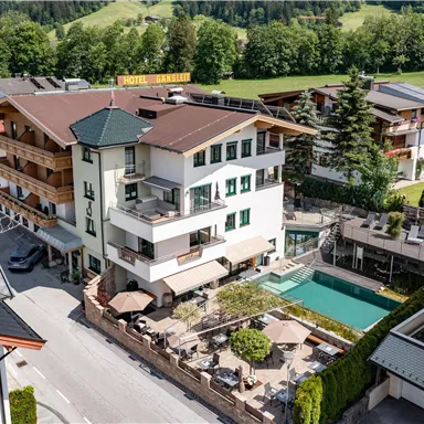 Ein modernes Hotel mit mehreren Gebäuden und einem Schwimmbad. Die Umgebung ist grün und bietet eine malerische Aussicht.