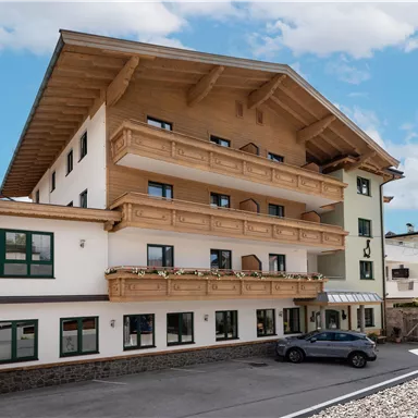 Ein modernes Gebäude mit mehreren Etagen und einem charmanten Holzdesign. Es steht in einer ruhigen Umgebung unter einem blauen Himmel.