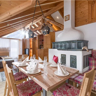 Ein gemütliches Wohnzimmer mit einem Esstisch, Holzdecke und traditionellem Kamin. Die Einrichtung ist rustikal und einladend.