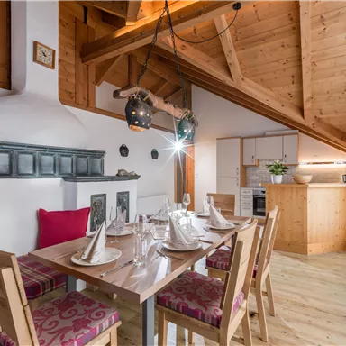 Ein modernes Esszimmer mit einem großen Tisch und gemütlichen Stühlen. Die Holzbalkendecke und die stilvolle Innenausstattung verleihen dem Raum eine einladende Atmosphäre.