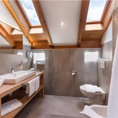 Ein modernes Bad mit Holzdetails und Dachfenstern. Es gibt eine große Waschtischfläche und sanitäre Einrichtungen.