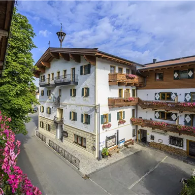 Ein malerisches Dorf mit traditionellen Gebäuden und blühenden Blumen. Die klare Luft und die Aussicht auf die Berge schaffen eine einladende Atmosphäre.