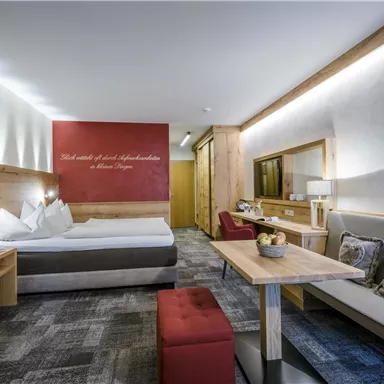 Ein modernes Hotelzimmer mit Holzmöbeln und einem gemütlichen Ambiente. Es gibt ein Doppelbett, einen Tisch und eine Sitzecke.