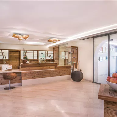 A modern reception area with wooden shelves and elegant lighting. In the foreground is a bowl of fresh apples.