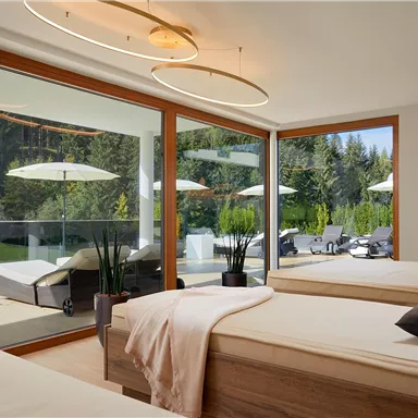 A modern bedroom with large windows and a view of nature. The decor is minimalist with two beds and stylish lights.