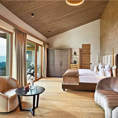 A modern room with large windows and a view of the mountains. The decor is bright and inviting with a comfortable sofa and a small table.