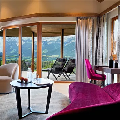 A modern living room with comfortable chairs and a large window that offers a view of the mountains. The decor is stylish and inviting.