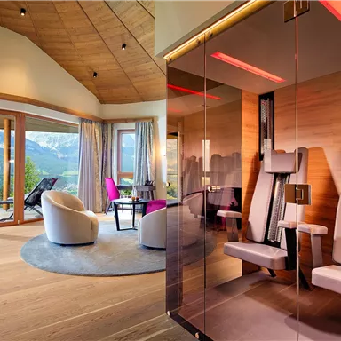 A modern wellness room with large windows and a view of the mountains. Stylish furniture and a relaxing atmosphere create an inviting environment.