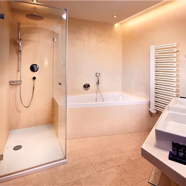 A modern bathroom with a shower and bathtub. Bright walls and elegant fixtures create a stylish atmosphere.