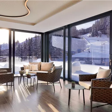 Ein modernes Wohnzimmer mit gemütlichen Sesseln und großen Fenstern. Draußen ist eine verschneite Landschaft zu sehen, umgeben von Bäumen.