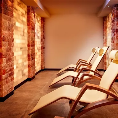 A relaxing rest room with comfortable loungers and soft lighting. The walls are designed with warm, stone-like materials.