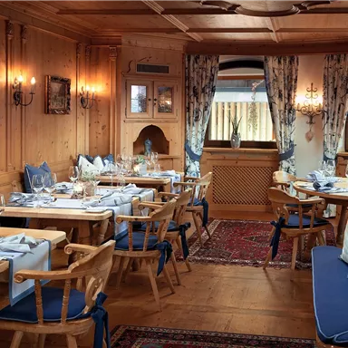 A cozy restaurant with wooden walls and blue seat cushions. The tables are neatly set and the ambiance is inviting.