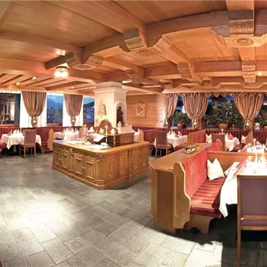 A cozy restaurant with wooden decor and white tablecloths. There are elegant tables and benches in an inviting atmosphere.