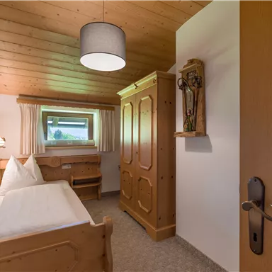 A cozy bedroom with wooden furniture and a window. The decor is simple and inviting, ideal for a relaxed atmosphere.