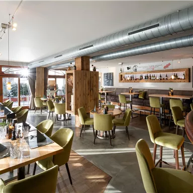 A modern restaurant with stylish furniture and bright lighting. The tables are elegantly set, and the overall atmosphere feels inviting.