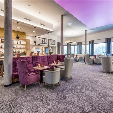 An elegant restaurant with modern furniture and cozy seating. The colorful ceiling and the large window front create an inviting atmosphere.