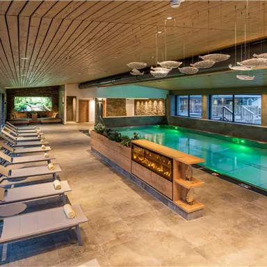 An elegant interior with a pool and loungers. Large windows provide plenty of natural light and create a modern, relaxed atmosphere.