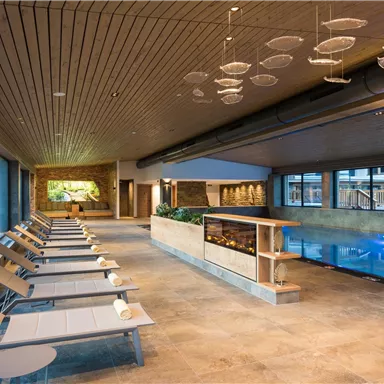 An elegant wellness area with loungers and an indoor pool. Large windows provide plenty of light and a relaxing atmosphere.