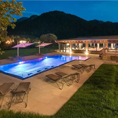 A modern house with a beautiful outdoor pool. The surroundings are green and mountainous, perfect for evening relaxation.