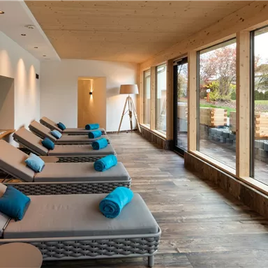 A modern wellness area with comfortable loungers and large windows. The room is bright and invites relaxation.