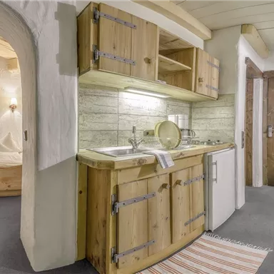 Eine gemütliche Küche aus Holz mit einfacher Ausstattung. Der Raum hat einen rustikalen Charme und eine helle Atmosphäre.