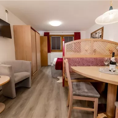 Ein gemütliches Apartment mit einem Essbereich und einem Schlafzimmer im Hintergrund. Die Einrichtung ist modern und einladend, ideal für einen entspannten Aufenthalt.