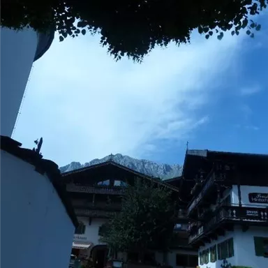 A traditional building in a picturesque mountain landscape. The sky is overcast, and the surroundings feel calm and inviting.