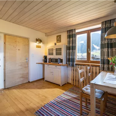 Eine gemütliche Küche mit Holzfußboden und einem großen Fenster. Der Raum ist hell erleuchtet und lädt zum Verweilen ein.