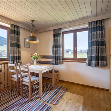 Ein gemütlicher Essbereich mit einem Holztisch und Stühlen. Große Fenster bieten einen Blick auf die Landschaft.
