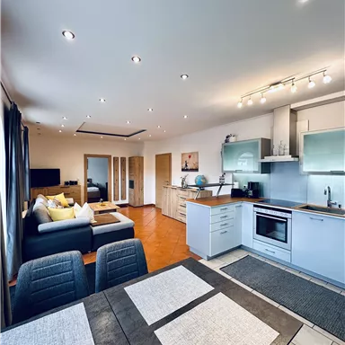 Eine moderne Wohnung mit offener Küche und gemütlichem Wohnzimmer. Helle Farben und stilvolle Möbel schaffen eine einladende Atmosphäre.