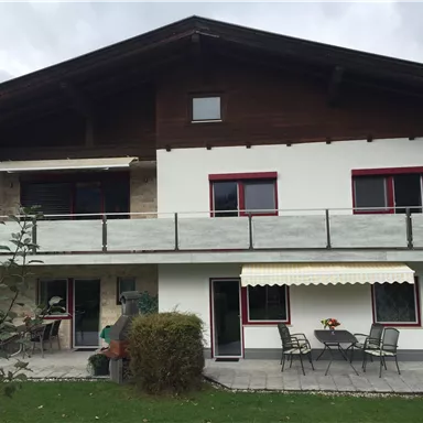 Ein modernes Haus mit einem großen Balkon und einer schönen Terrasse. Der Garten ist gepflegt und lädt zum Entspannen ein.