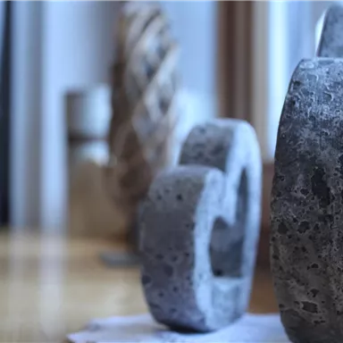 Kunstvolle Betonobjekte stehen auf einem Tisch. Sie sind in unterschiedlichen Größen und Formen angeordnet.