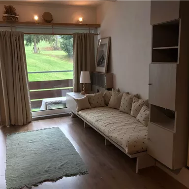 A cozy living space with a bright sofa and a terrace. Large windows let in plenty of daylight and offer a view of the greenery.