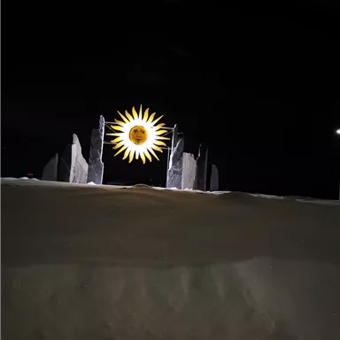 A radiant sunrise over a snow-covered landscape. In the foreground, some stones are visible, adding a mystical atmosphere to the image.