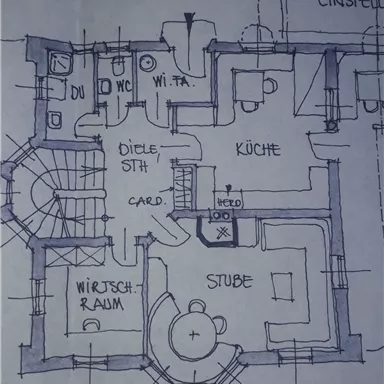 Ein Grundriss eines Hauses mit verschiedenen Zimmern, wie Küche, Stube und Wirtschaftraum. Die Zeichnung zeigt auch eine Treppe und den Eingangsbereich.