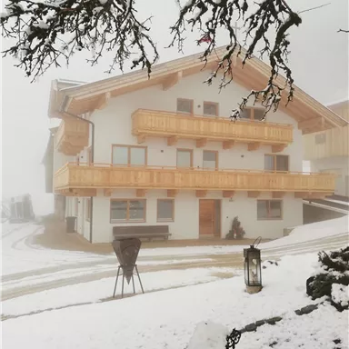 A cozy house with wooden balustrades, surrounded by snow and fog. The wintry landscape conveys a calm and peaceful atmosphere.