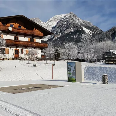 A beautiful wooden house in a snowy landscape. The mountain backdrop in the background is impressive.