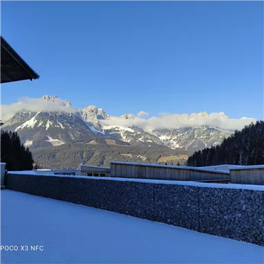 A winter landscape with snow-covered mountains and clear blue skies. The scenery is peaceful and picturesque, perfect for nature lovers.