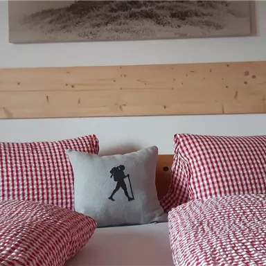 Ein gemütliches Schlafzimmer mit zwei Betten und kariertem Bettzeug. An der Wand hängen zwei Nachttischlampen und ein dekoratives Bild.
