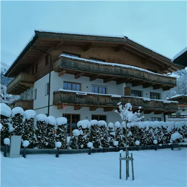 A cozy chalet in winter with fresh snow. The balconies are made of wood and the surroundings are picturesque.