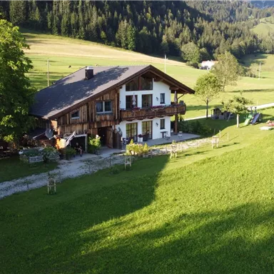 Ein charmantes Haus inmitten von weiten grünen Wiesen und sanften Hügeln. Die Umgebung strahlt eine ruhige ländliche Idylle aus.