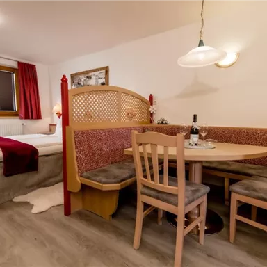 Ein komfortables Zimmer mit einem Bett und einer gemütlichen Sitzecke. Der Tisch ist gedeckt und es gibt eine angenehme Atmosphäre.