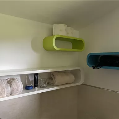 A modern bathroom with colorful shelves. Towels and toiletries are neatly stored.