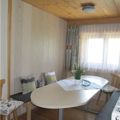 Ein heller Raum mit einem ovalen Tisch und Stühlen. Große Fenster lassen viel Tageslicht herein.