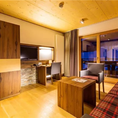Ein modernes Zimmer mit Holzverkleidung und gemütlichem Ambiente. Es verfügt über einen Fernseher, einen Schreibtisch und Zugang zu einem Balkon.