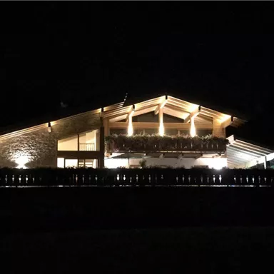 Ein modernes Haus bei Nacht, schön beleuchtet. Die Gestaltung kombiniert Holz und Stein, was eine warme Atmosphäre schafft.